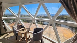 A room with a large glass window, a wooden deck, and two chairs.
