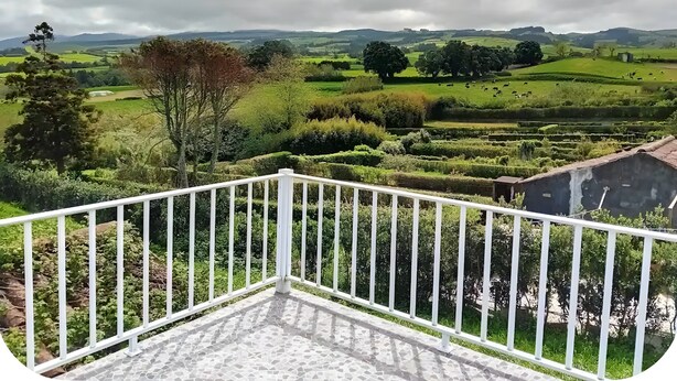 A balcony with a white railing overlooking a green landscape with trees and fields. - Holiday Home 'Casa Do Pacheco' with Sea View, Wi-Fi and Air Conditioning (Salga)