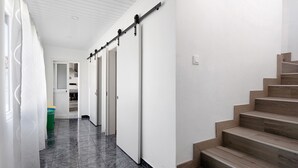 A hallway with a sliding door, a staircase, and a trash bin. - Holiday Home 'Casa Do Pacheco' with Sea View, Wi-Fi and Air Conditioning (Salga)
