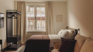 A hotel room with a bed, a sofa, a wardrobe, and a window with curtains. - Copla Bilbao (Bilbao)