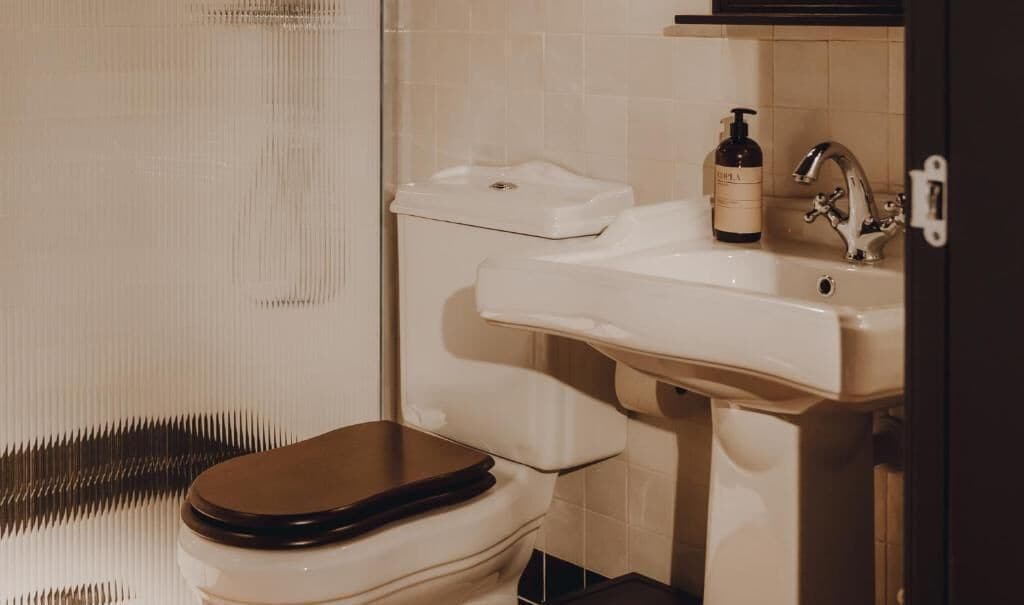 A bathroom with a toilet, sink, and a bottle of hand soap.