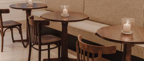 A seating area with a sofa and two round tables, each with a candle.