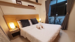 A neatly made bed with pillows, a bedside lamp, and a small table with a plant.
