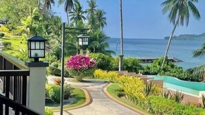 A pathway leading to a beach with palm trees and a view of the ocean.