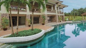 A pool area with a building, palm trees, and a gazebo.