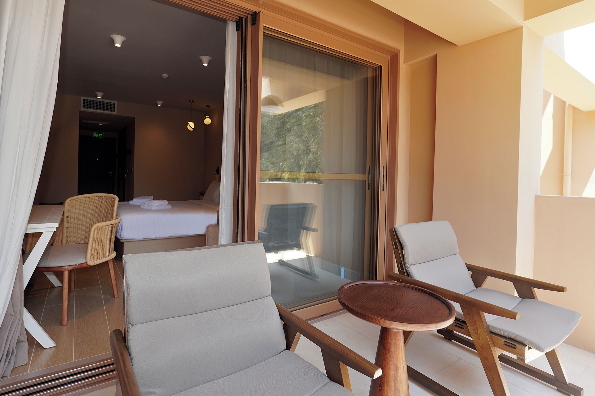 Habitación de hotel con balcón, cama, silla, mesa y vistas al exterior.