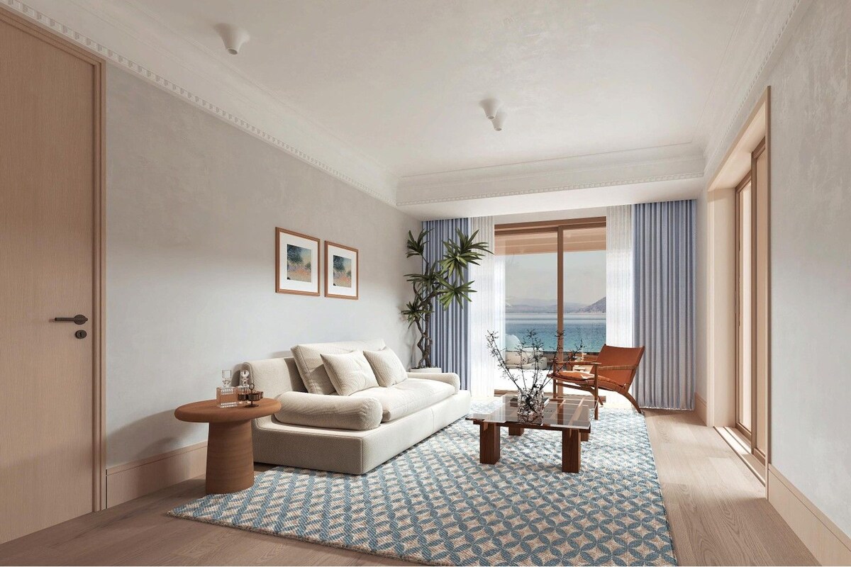 A modern living room with a sofa, coffee table, and a view of the sea.