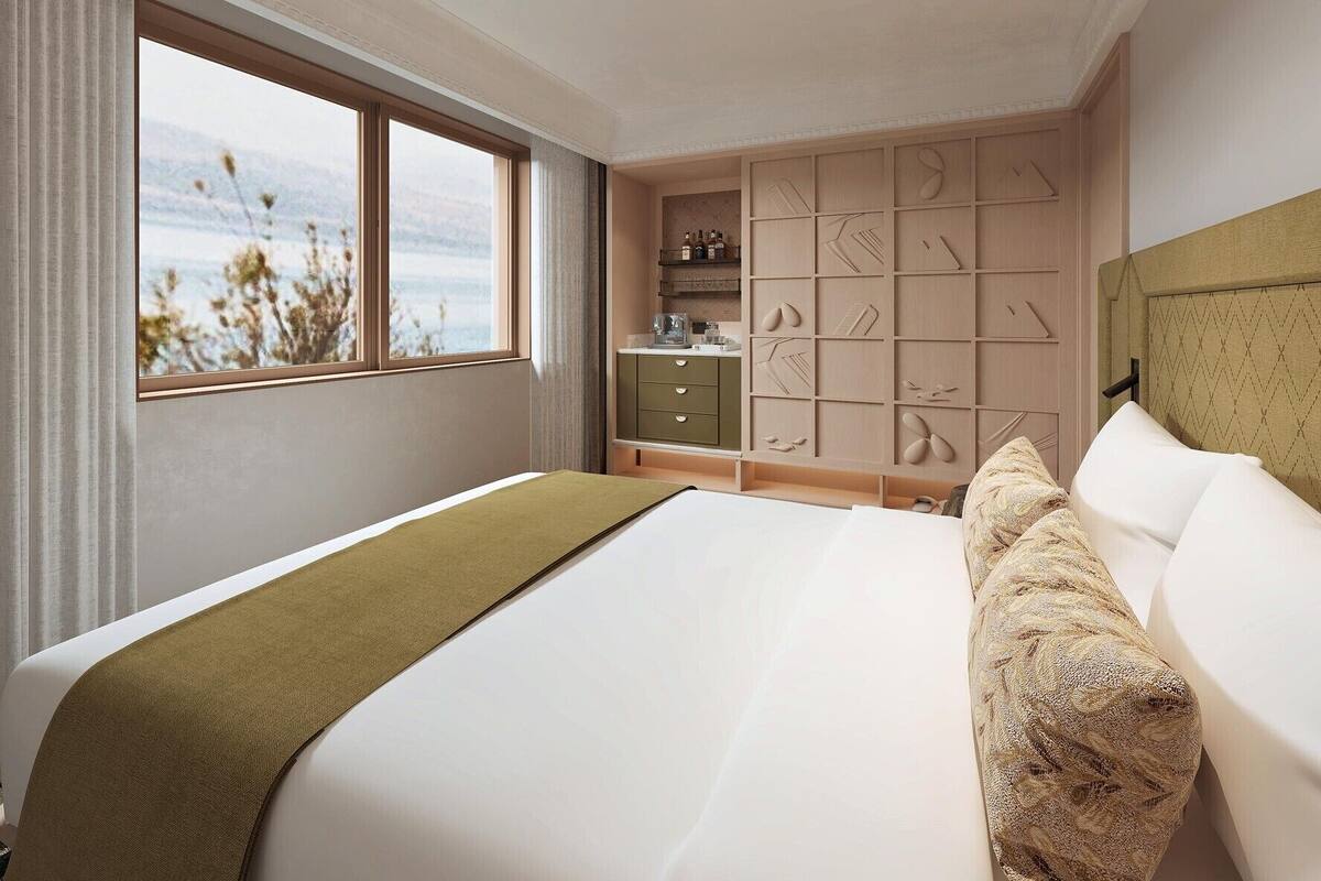 A hotel room with a large bed, a view of the outdoors, a built-in wardrobe, and a bedside table.