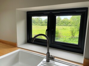 Ein Badezimmer mit Fenster, Waschbecken und Blick auf eine grüne Landschaft.