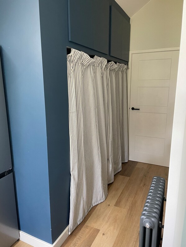 Une pièce avec un mur bleu foncé, une porte blanche et un rideau à rayures.