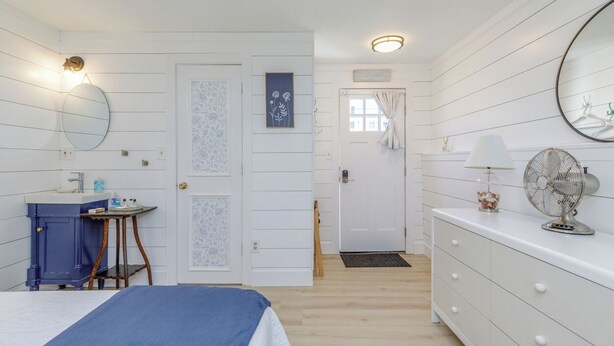A bedroom with a bed, a dresser, a mirror, a fan, and a door leading to another room. - Steps to Ogunquit Beach, Dining and Shops.  Sitting in the heart of Ogunquit! (Ogunquit)