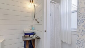 A bathroom with a sink, mirror, and shower curtain. - Steps to Ogunquit Beach, Dining and Shops.  Sitting in the heart of Ogunquit! (Ogunquit)