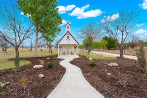 A church with a white steeple, a cross at the top, and a pathway leading to the entrance. - Vista Moon: Cabin G - Pool, Chapel, Fire Pit (Fredericksburg)