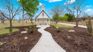 A church with a white steeple, a cross at the top, and a pathway leading to the entrance. - Vista Moon: Cabin D - Pool, Chapel, Fire Pit (Fredericksburg)