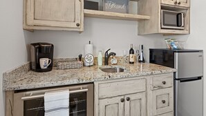 A kitchen with a granite countertop, a coffee maker, a sink, a microwave, and a refrigerator. - Vista Moon: Cabin D - Pool, Chapel, Fire Pit (Fredericksburg)