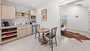 Una cocina con armarios de madera, una mesa de comedor con sillas, un refrigerador y una alfombra de cuero de vaca.