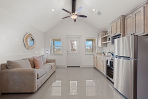 Una cocina moderna con ventilador de techo, refrigerador y comedor con sofá.