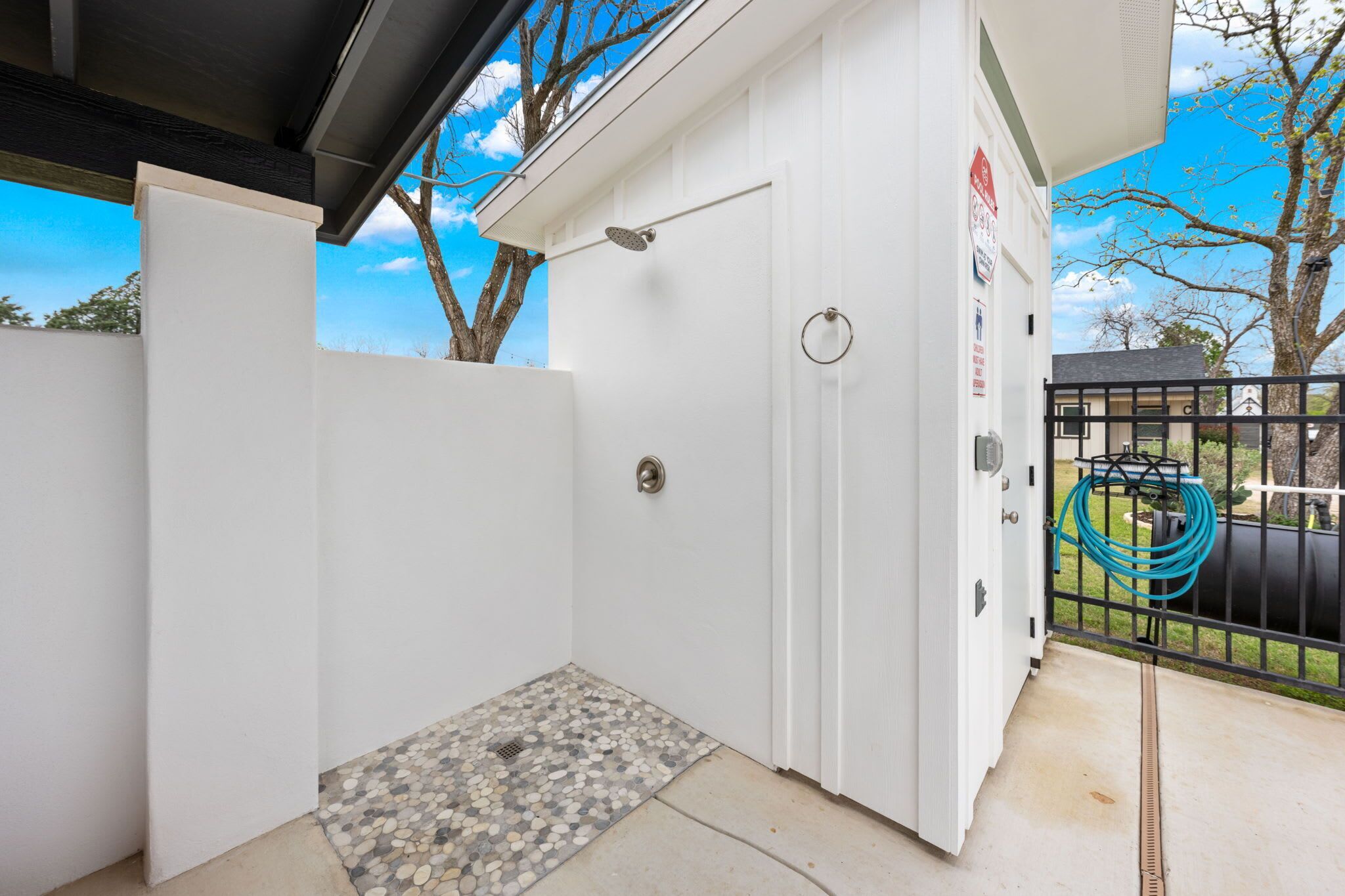 A white room with a shower, a door, a window, and a view of a tree and sky.