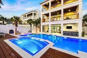 A multi-story building with a swimming pool, outdoor seating, and a bar area. - Seas The Moment|Easy Beach Access|Large Private Pool|Golf Cart (Destin)