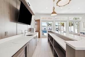 A modern kitchen with a large island, built-in appliances, and a flat-screen TV. - Seas The Moment|Easy Beach Access|Large Private Pool|Golf Cart (Destin)