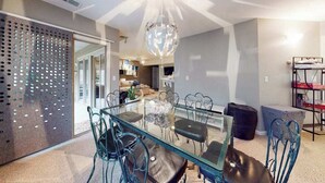 Un espace repas moderne avec une table en verre et des chaises en métal, un lustre décoratif en forme de globe et un séparateur en métal ajouré.