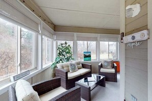 A sunroom with wicker furniture, large windows, and a plant. - The Plantations condo with sunroom - near beach (Lewes)