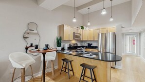 A modern kitchen with a central island, bar stools, a microwave, a refrigerator, and pendant lighting. - Upscale condo in heart of Dewey with pool & AC - walk to beach, bay & hot spots (Dewey Beach)