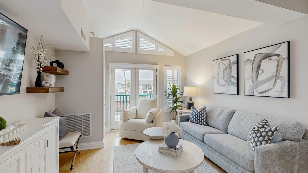 A modern living room with a sofa, armchair, coffee table, and artwork.