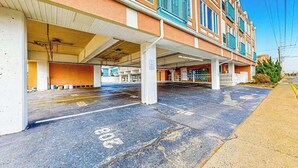 A multi-story building with a covered parking area and a visible entrance. - Upscale condo in heart of Dewey with pool & AC - walk to beach, bay & hot spots (Dewey Beach)
