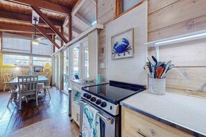 Una cocina con estufa, armarios de madera y un comedor con mesa y sillas.