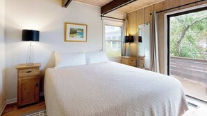 A bedroom with a bed, bedside tables, lamps, a painting, and a window with a view.