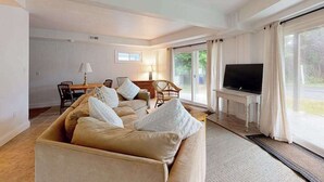 A living room with a sofa, a TV, and a dining area.