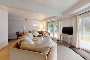 A living room with a sofa, a TV, and a dining area.