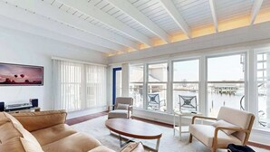 A spacious living room with a large window, a sofa, a coffee table, and a chair. - Town of Lewes condo steps from the park w/Tennis, Pickleball & Basketball (Lewes)