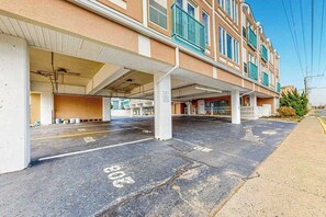 A building with a covered parking area and a row of rooms with balconies. - Town of Dewey Beach updated condo with pool, balcony, & W/D (Dewey Beach)