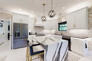 A modern kitchen with white cabinetry, a marble island, and a built-in oven. - Town of Lewes home with private pool, patio and balcony (Lewes)