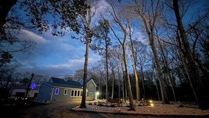 Une maison entourée d’arbres au crépuscule.