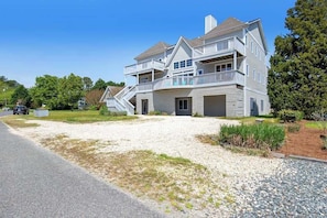 A two-story house with a front porch, a driveway, and a gravel area. - Quillens Point home w/ 5 decks, screened porch, grill & shared tennis - dogs OK (Ocean View)