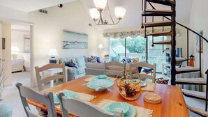 Un coin repas avec une table en bois, des chaises et un lustre.