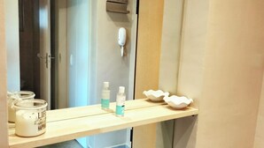 Une salle de bain avec un miroir, une étagère sur laquelle se trouvent une bougie, une bouteille et un bol.