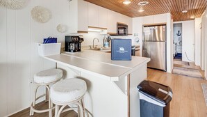 Una cucina moderna con mobili bianchi, soffitto in legno e frigorifero in acciaio inossidabile.
