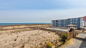 Un hotel sulla spiaggia con piscina, una recinzione in legno e vista sull'oceano.