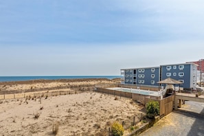 Ein Strandhotel mit Pool, Holzzaun und Blick auf den Ozean.