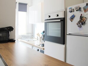 Uma cozinha moderna com forno embutido, máquina de café e geladeira com imãs.