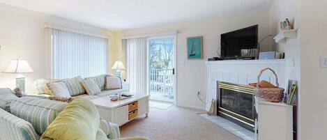 A living room with a sofa, a coffee table, a fireplace, and a television.