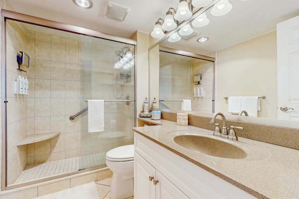 A modern bathroom with a glass shower enclosure, a sink with a vanity, and a large mirror.