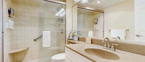 A modern bathroom with a glass shower enclosure, a sink with a vanity, and a large mirror.