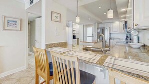 A modern kitchen with granite countertops, stainless steel appliances, and pendant lighting. - Sea Colony condo in oceanside complex with washer/dryer, shared hot tub & pool (Bethany Beach)