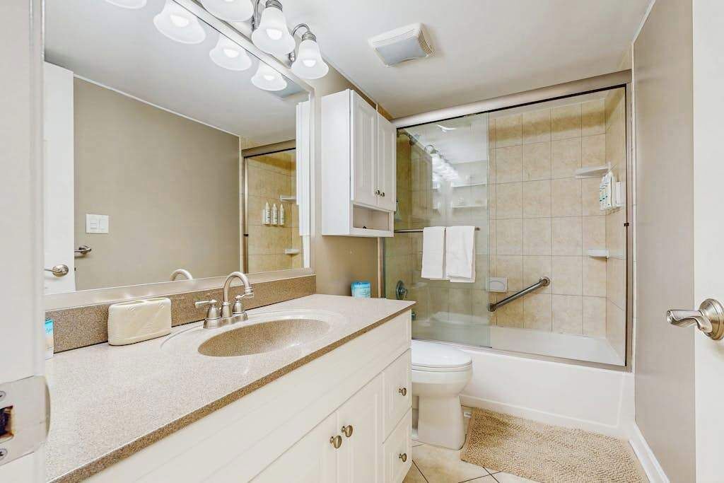 Un baño con lavamanos, espejo, armarios y cabina de ducha de vidrio.