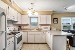 A kitchen with white cabinets, a microwave, a stove, and a sink.